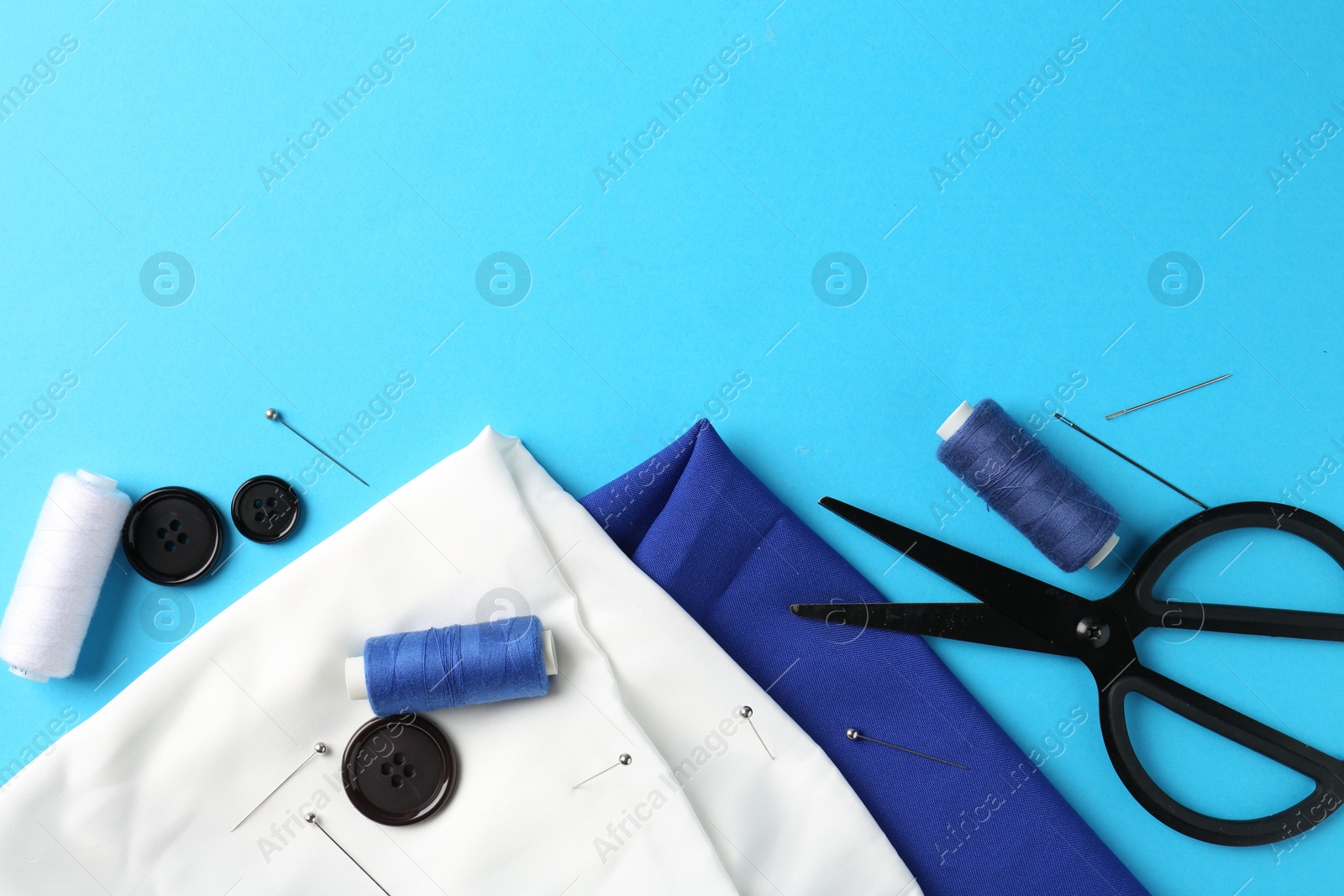 Photo of Different sewing supplies on light blue background, flat lay. Space for text