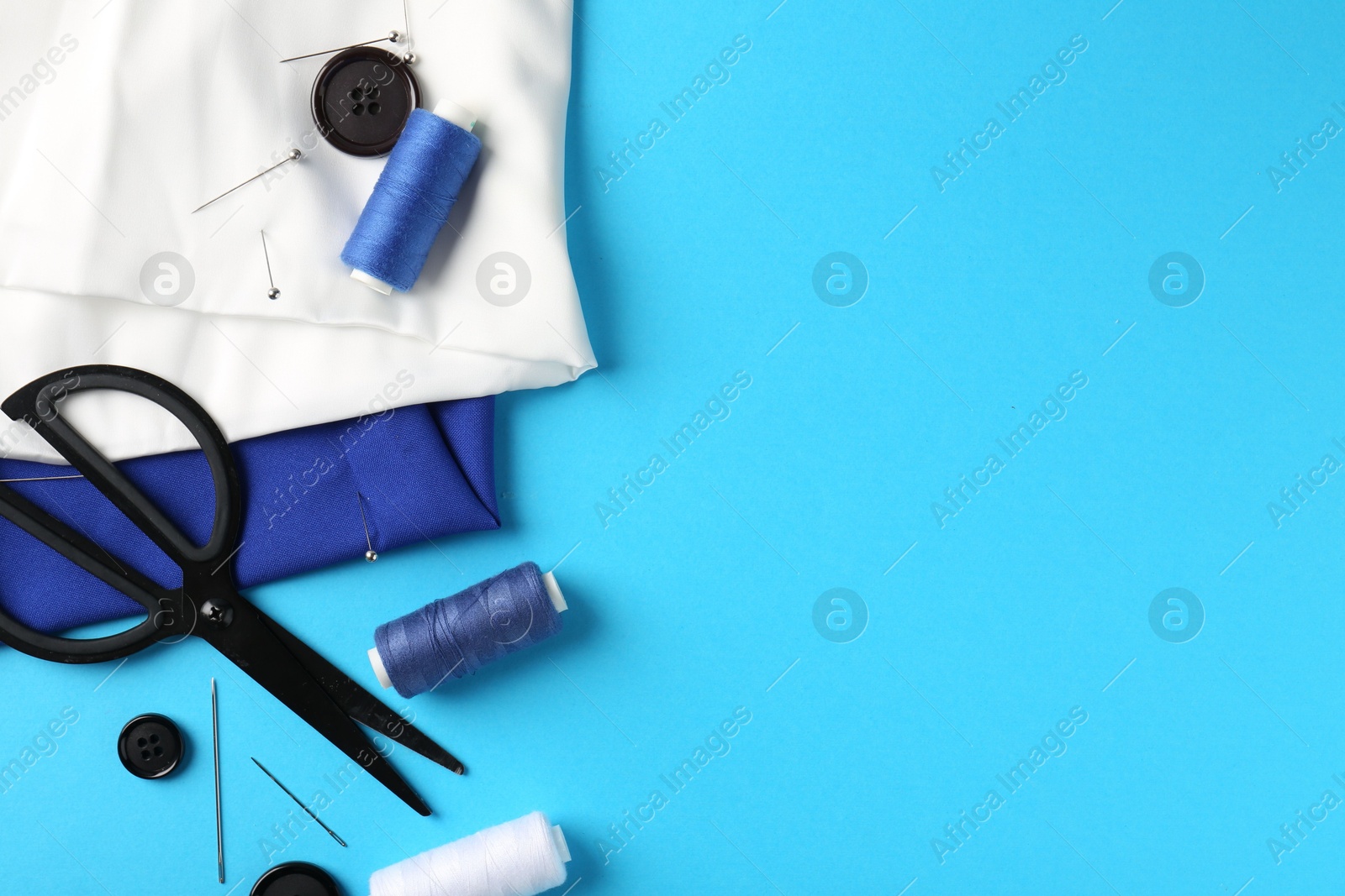 Photo of Different sewing supplies on light blue background, flat lay. Space for text