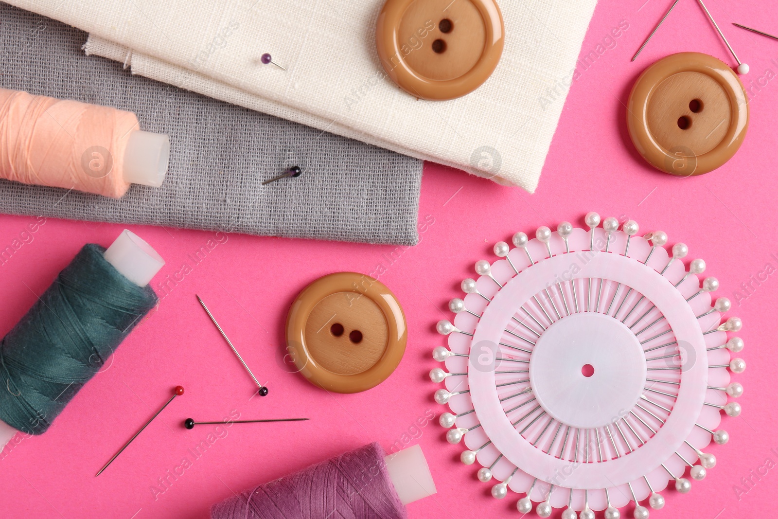 Photo of Different sewing supplies on pink background, flat lay