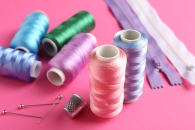 Photo of Different sewing supplies on pink background, closeup