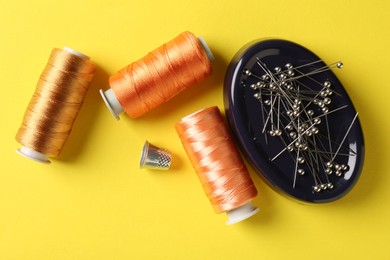 Photo of Different sewing supplies on yellow background, flat lay