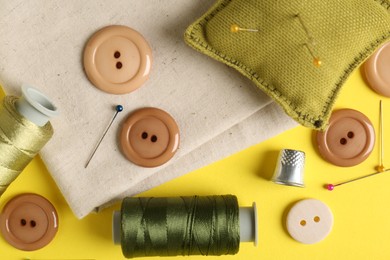 Photo of Different sewing supplies on yellow background, flat lay