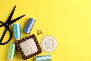 Photo of Different sewing supplies on yellow background, flat lay. Space for text