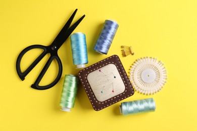 Photo of Different sewing supplies on yellow background, flat lay