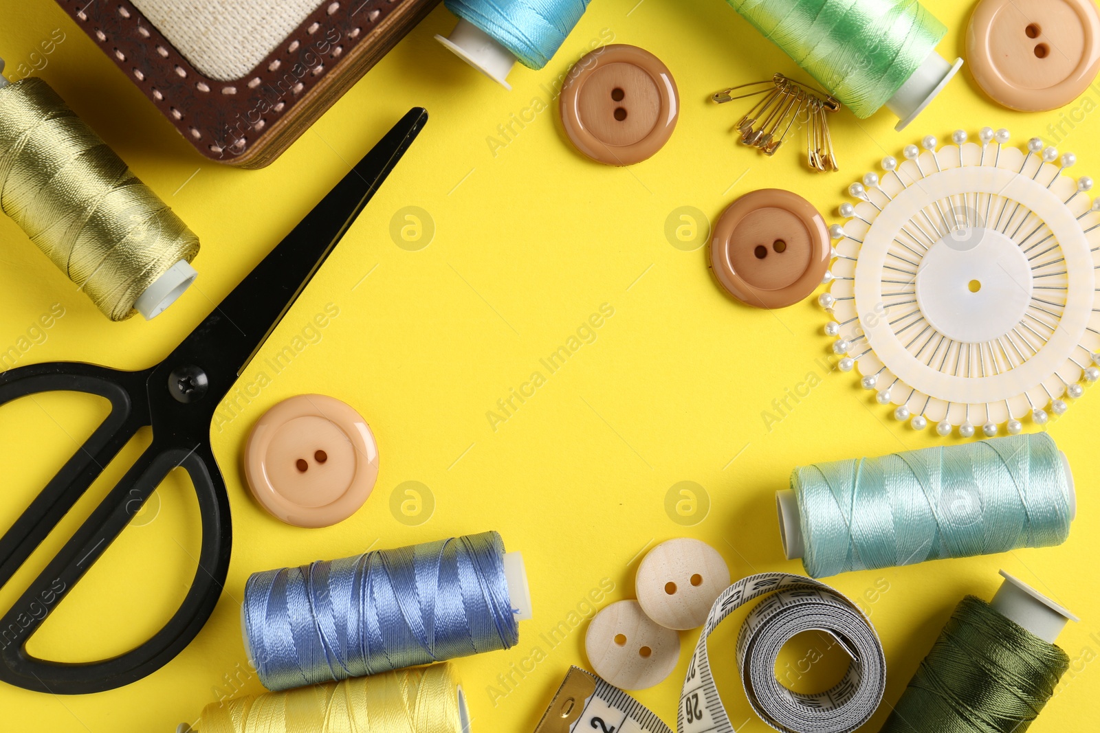 Photo of Frame made of different sewing supplies on yellow background, flat lay. Space for text