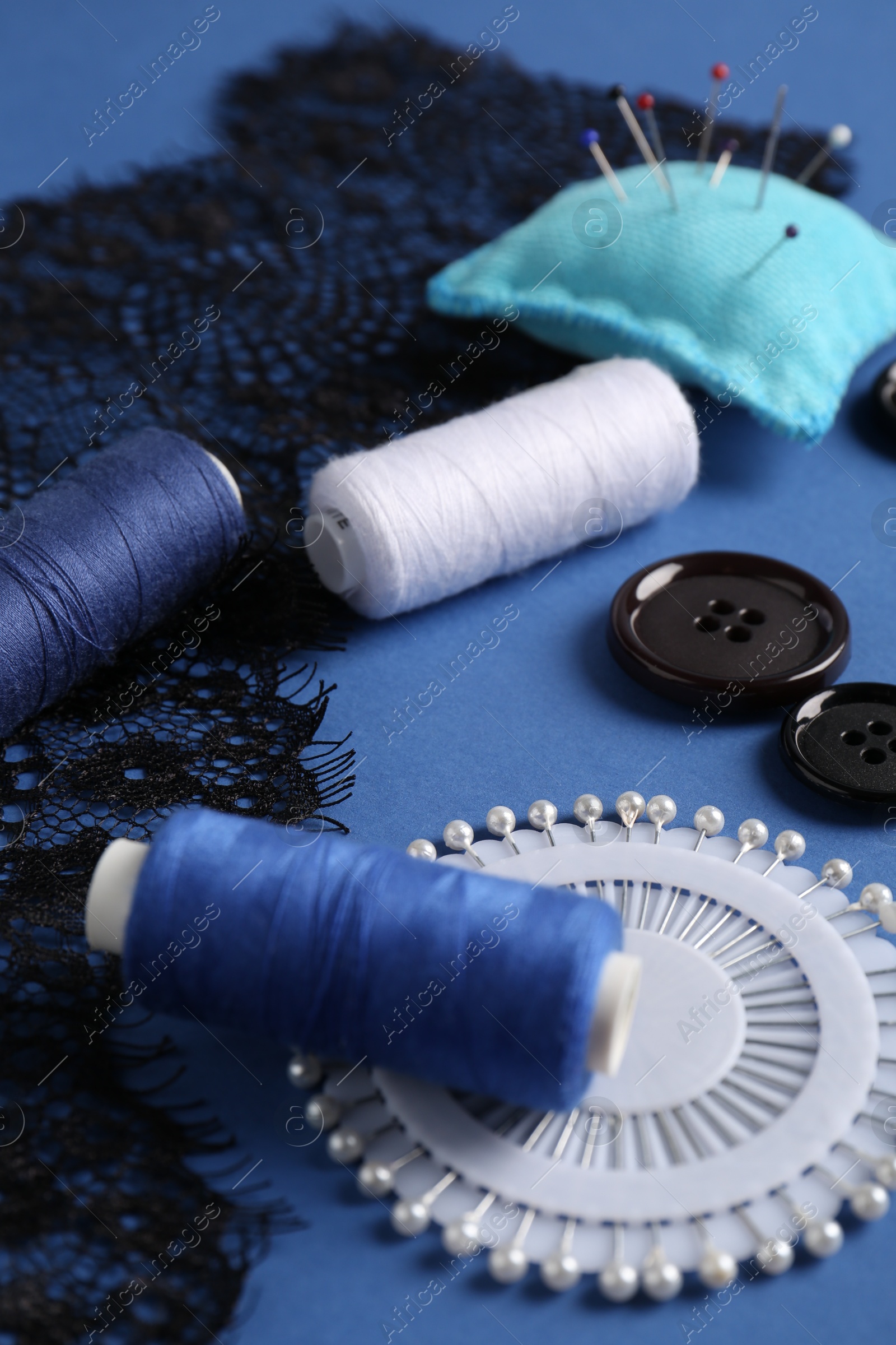 Photo of Different sewing supplies on blue background, closeup