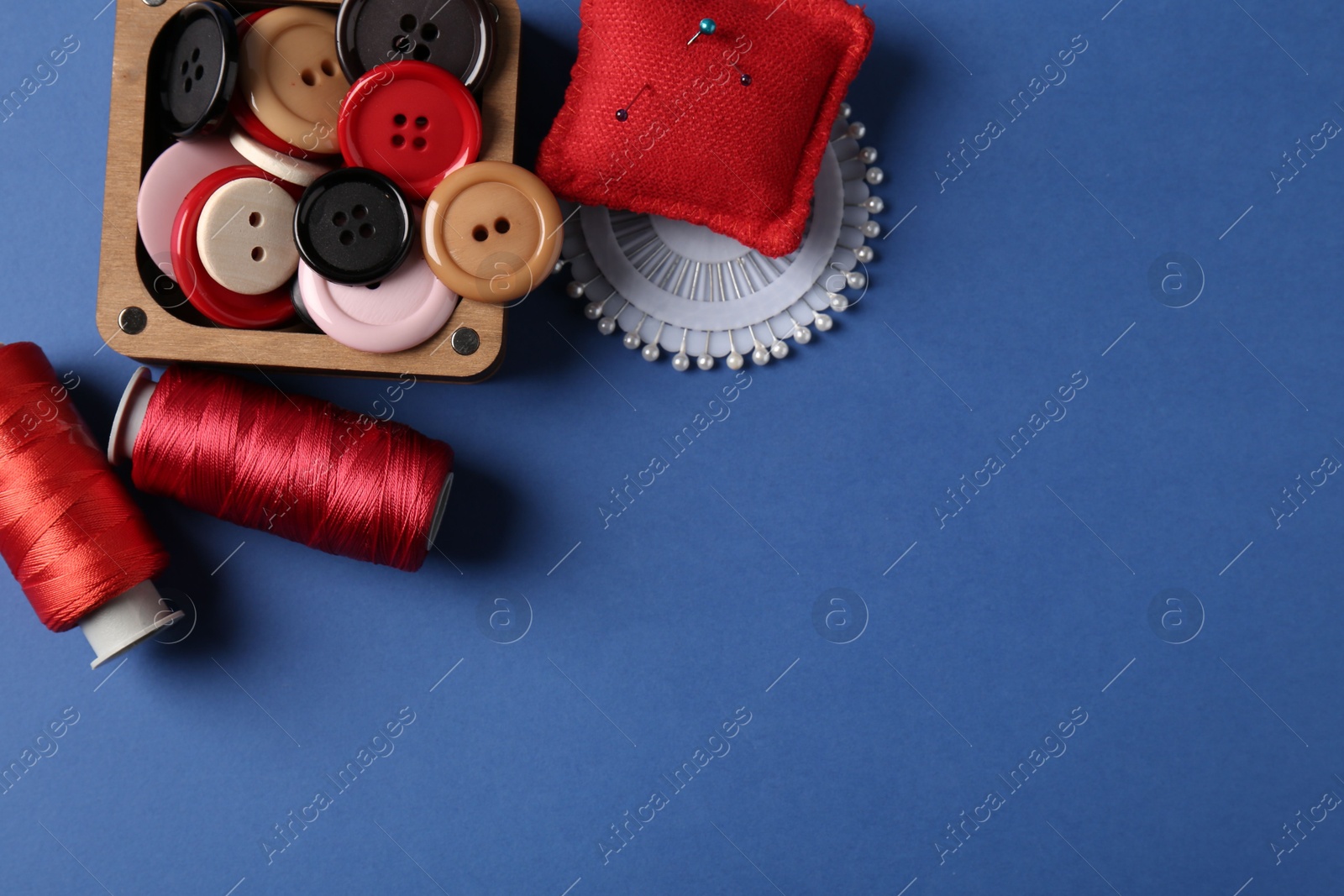 Photo of Different sewing supplies on blue background, flat lay. Space for text