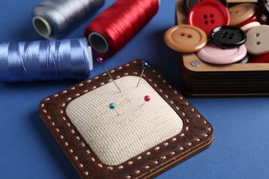 Photo of Different sewing supplies on blue background, closeup