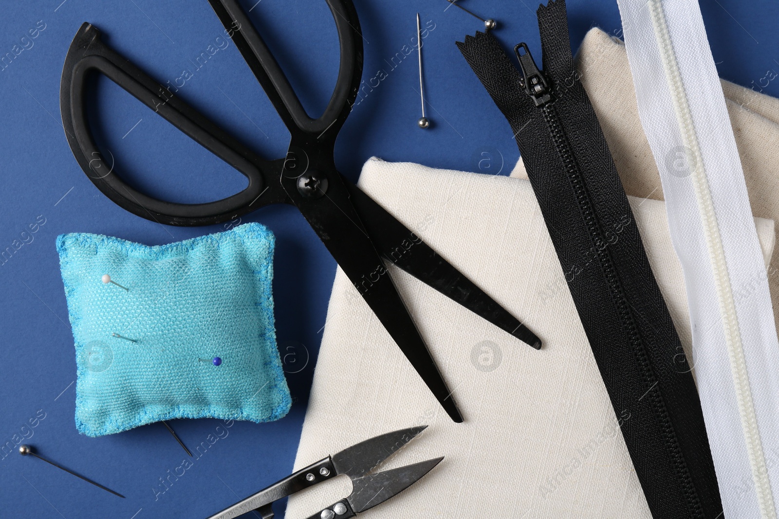 Photo of Different sewing supplies on blue background, flat lay