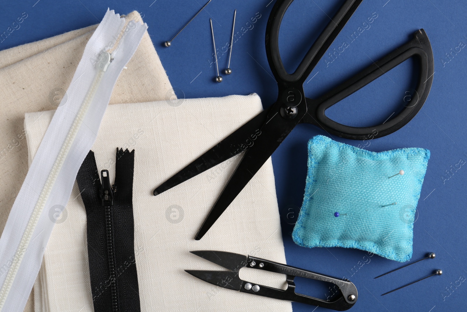 Photo of Different sewing supplies on blue background, flat lay