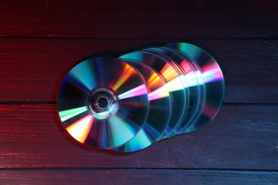 Shiny compact discs on wooden background, top view