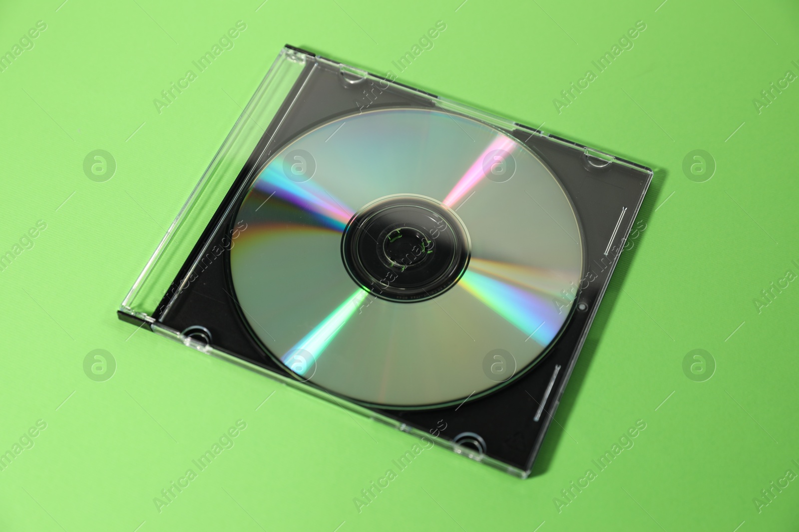 Photo of One compact disc in jewel case on green background, closeup