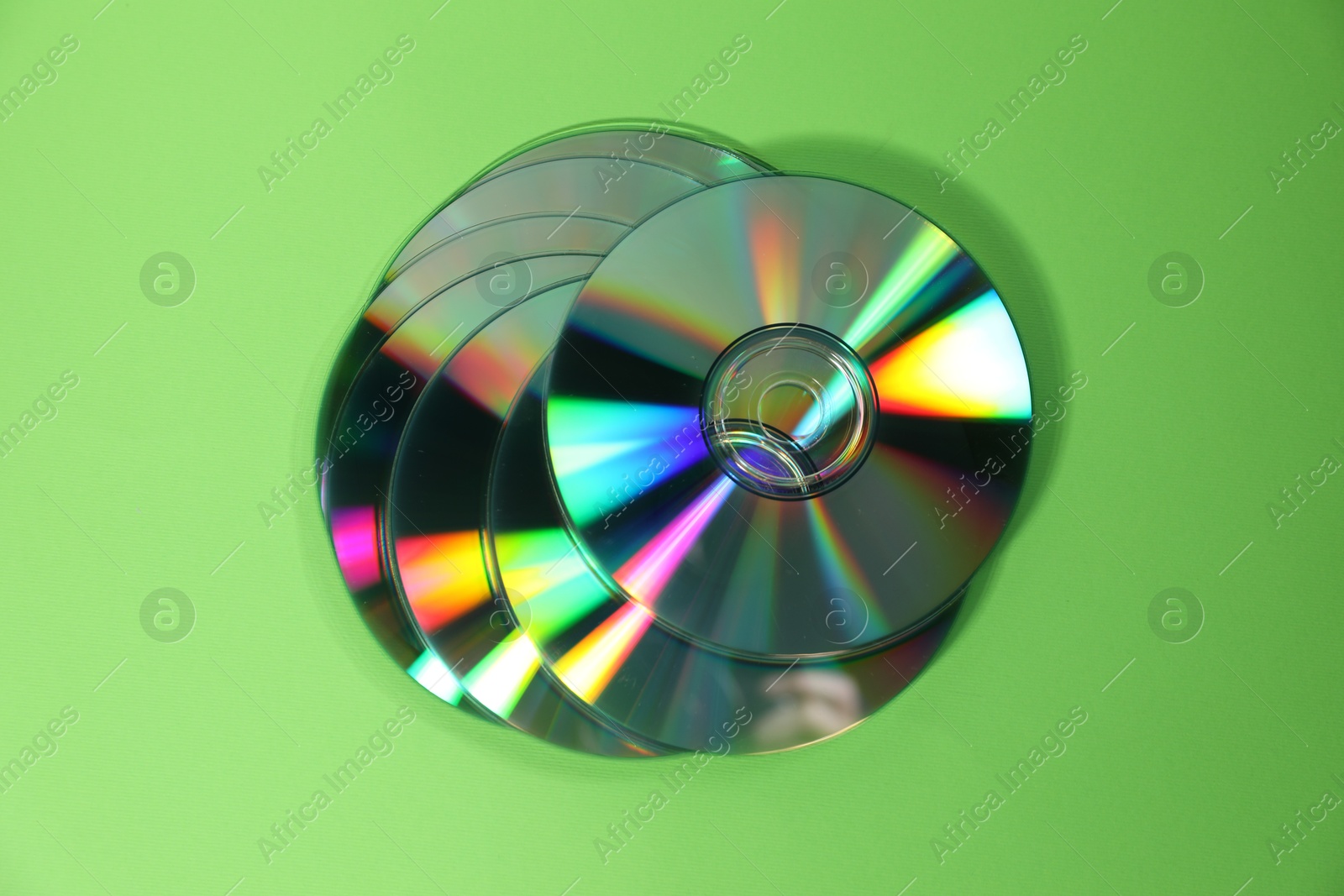 Photo of Many compact discs on green background, top view