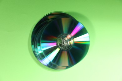 Photo of Many compact discs on green background, top view