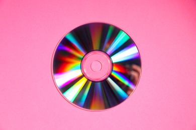 Photo of One shiny compact disc on pink background, top view