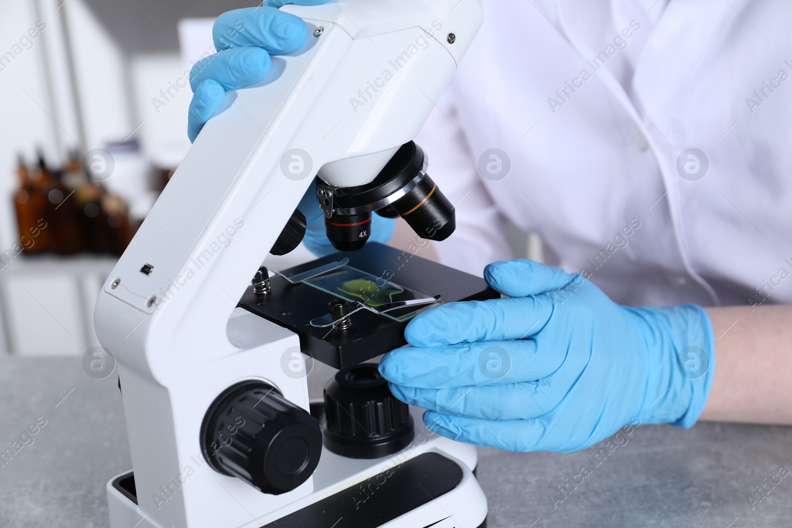 Photo of Laboratory testing. Scientist examining sample on slide under microscope indoors, closeup