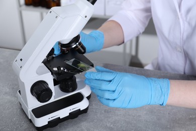 Photo of Laboratory testing. Scientist examining sample on slide under microscope indoors, closeup