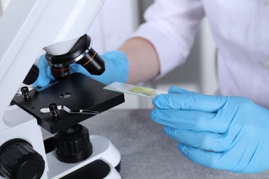 Photo of Laboratory testing. Scientist examining sample on slide under microscope indoors, closeup