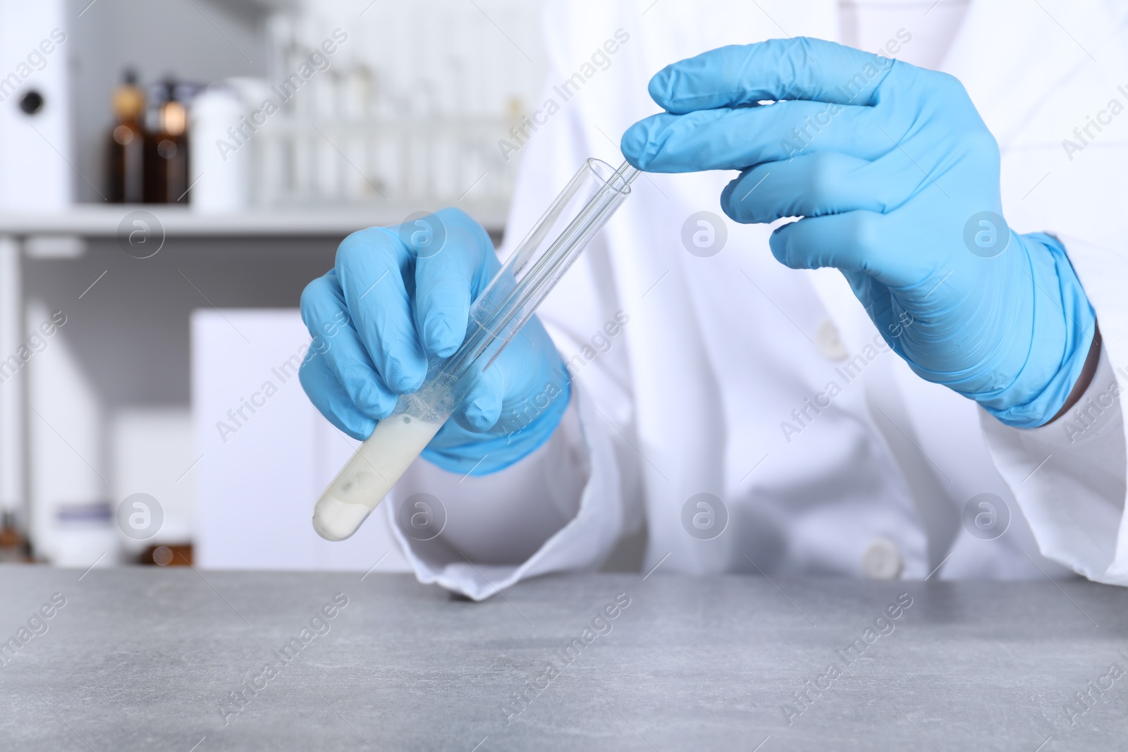 Photo of Laboratory testing. Scientist taking sample from test tube at grey table, closeup