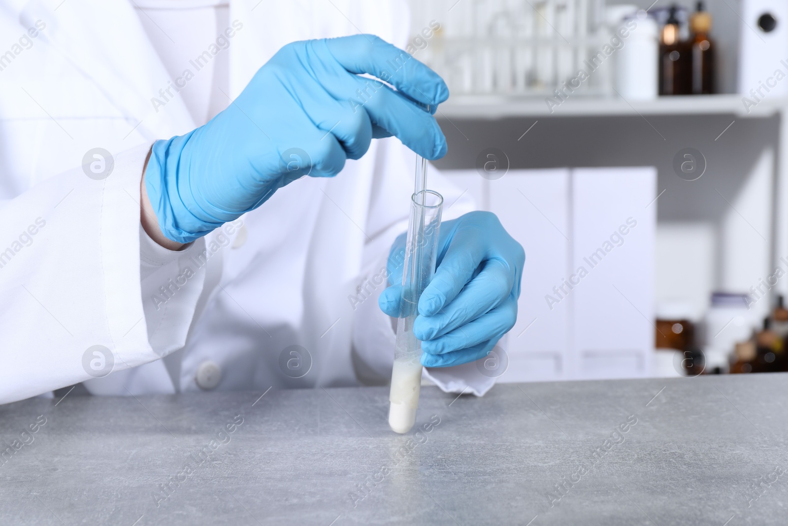 Photo of Laboratory testing. Scientist taking sample from test tube at grey table, closeup. Space for text