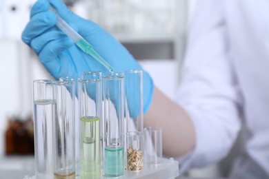 Photo of Laboratory testing. Scientist dripping sample from pipette into test tube indoors, closeup