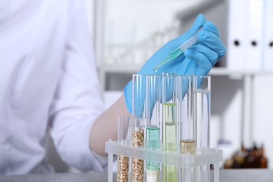 Photo of Laboratory testing. Scientist dripping sample from pipette into test tube indoors, closeup