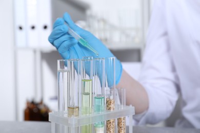 Photo of Laboratory testing. Scientist dripping sample from pipette into test tube indoors, closeup