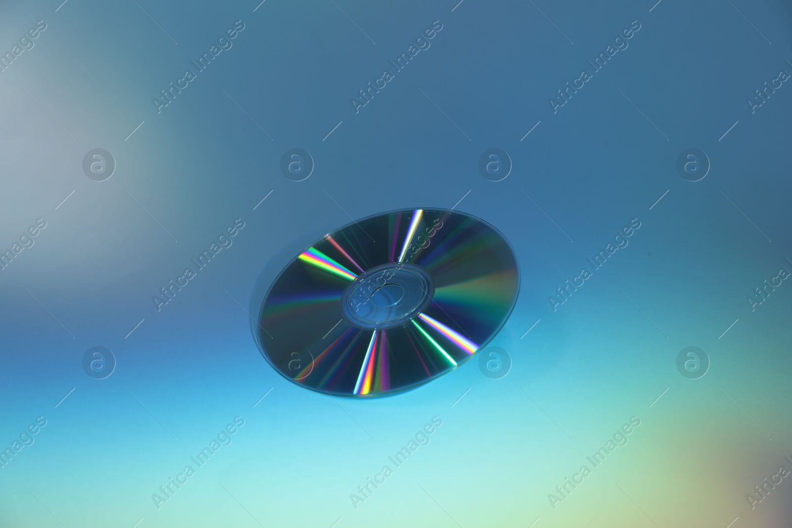 Photo of One shiny compact disc on light blue background