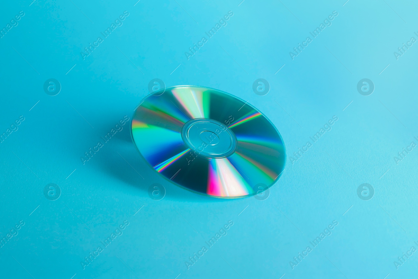 Photo of One shiny compact disc on light blue background