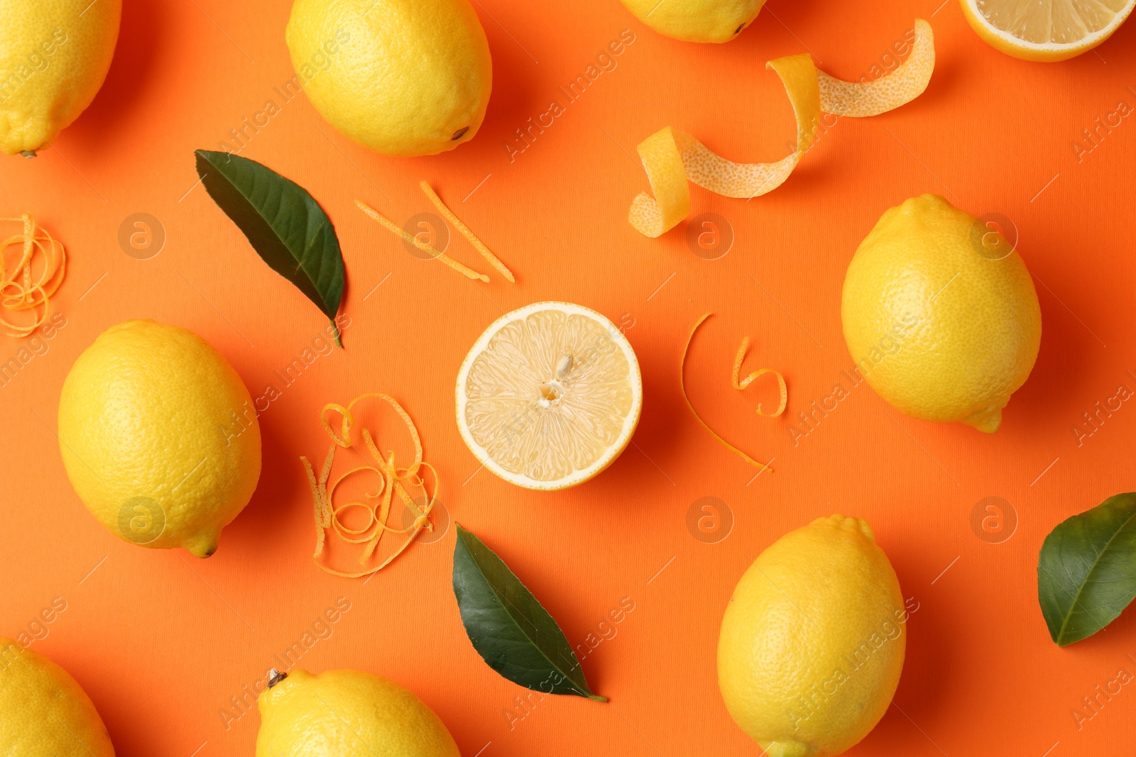 Photo of Lemon zest, fresh fruits and leaves on orange background, flat lay