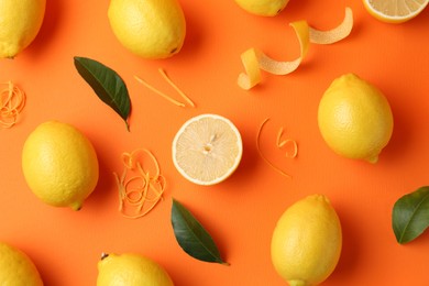 Photo of Lemon zest, fresh fruits and leaves on orange background, flat lay