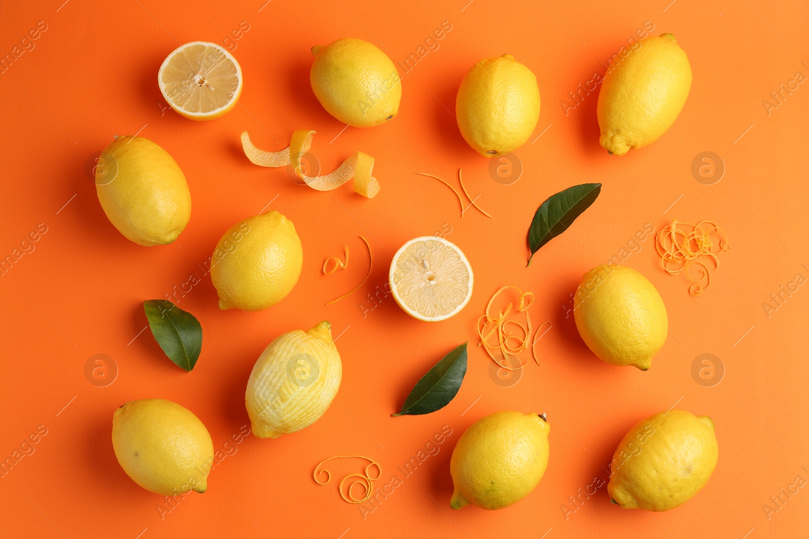 Photo of Lemon zest, fresh fruits and leaves on orange background, flat lay