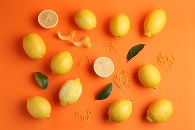 Photo of Lemon zest, fresh fruits and leaves on orange background, flat lay