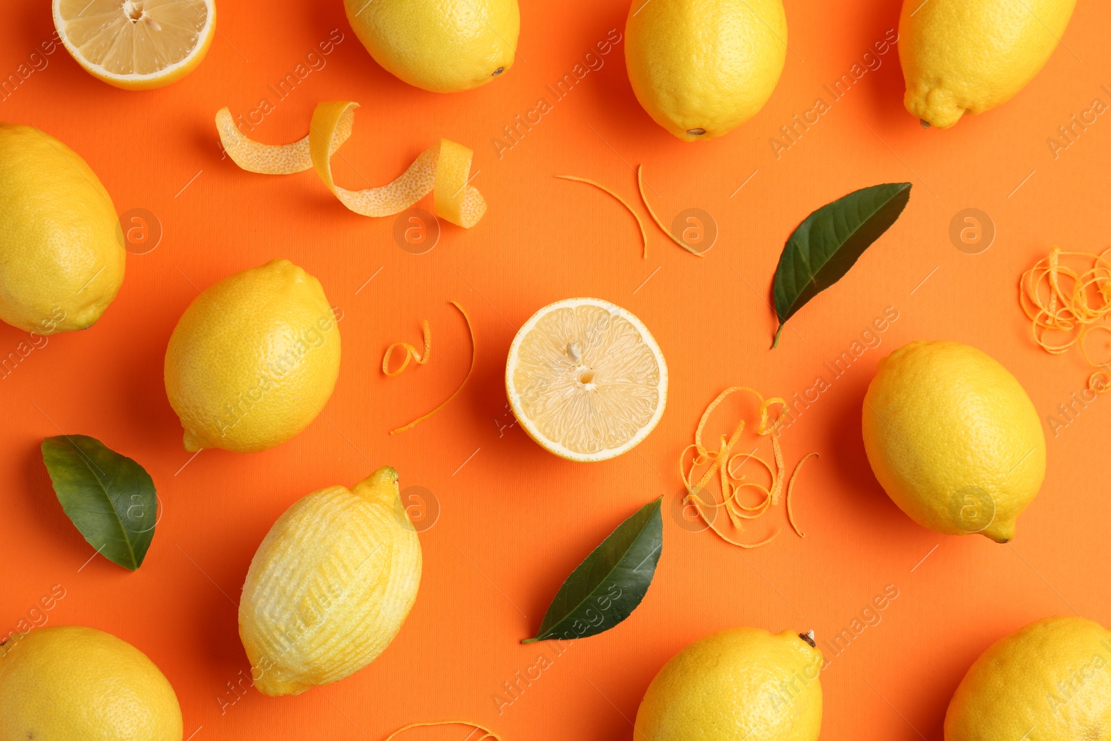 Photo of Lemon zest, fresh fruits and leaves on orange background, flat lay