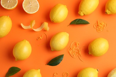 Photo of Lemon zest, fresh fruits and leaves on orange background, flat lay