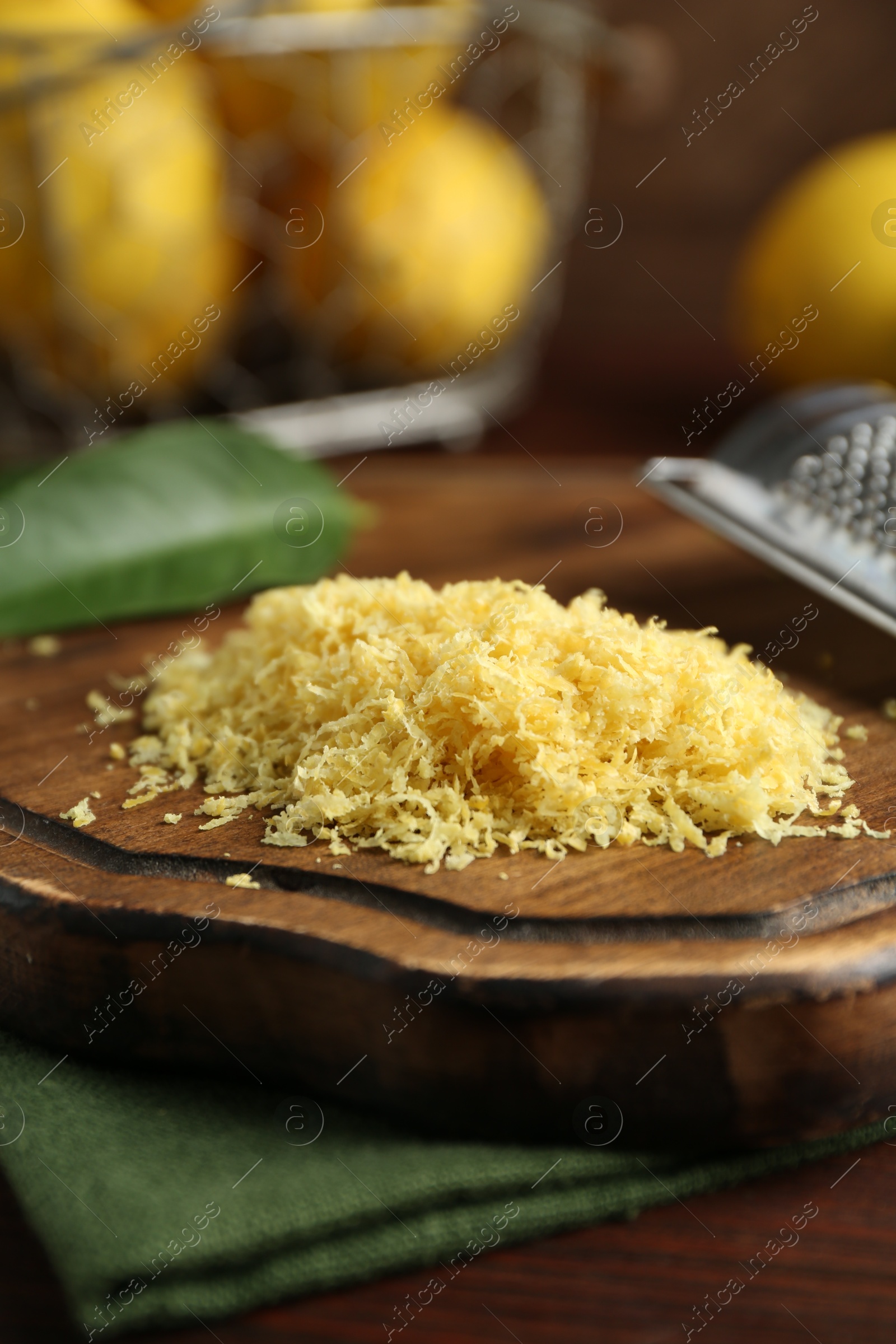 Photo of Lemon zest, grater and fresh fruits on wooden table, closeup