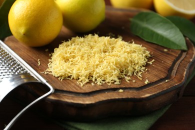 Photo of Lemon zest, grater and fresh fruits on wooden table, closeup