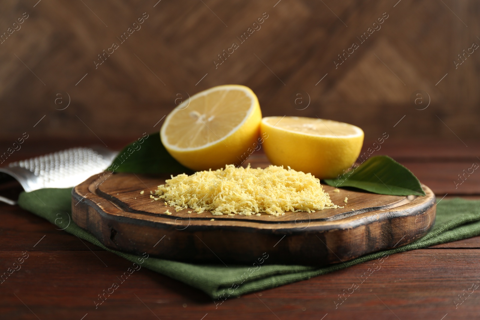 Photo of Lemon zest, grater and fresh fruit pieces on wooden table