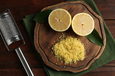 Photo of Lemon zest, grater and fresh fruit pieces on wooden table, top view