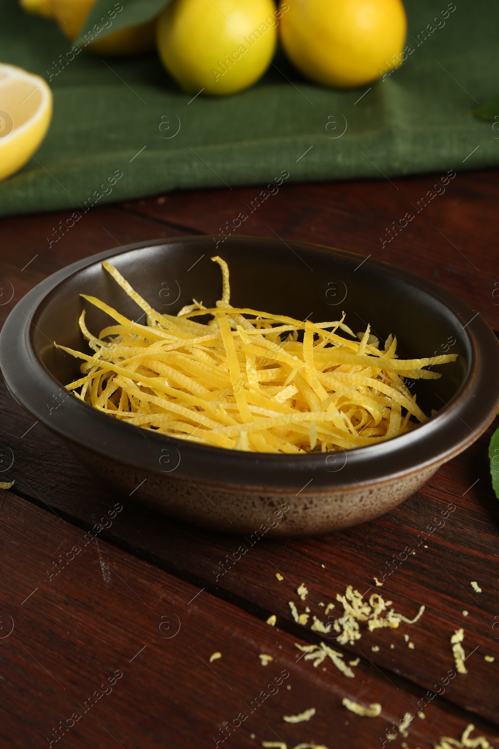 Photo of Lemon zest in bowl on wooden table, closeup