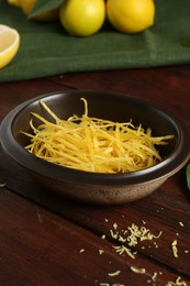 Photo of Lemon zest in bowl on wooden table, closeup