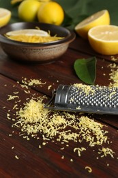 Photo of Lemon zest, grater and fresh fruits on wooden table, closeup