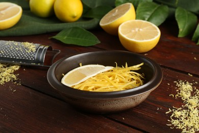 Photo of Lemon zest, grater and fresh fruits on wooden table, closeup