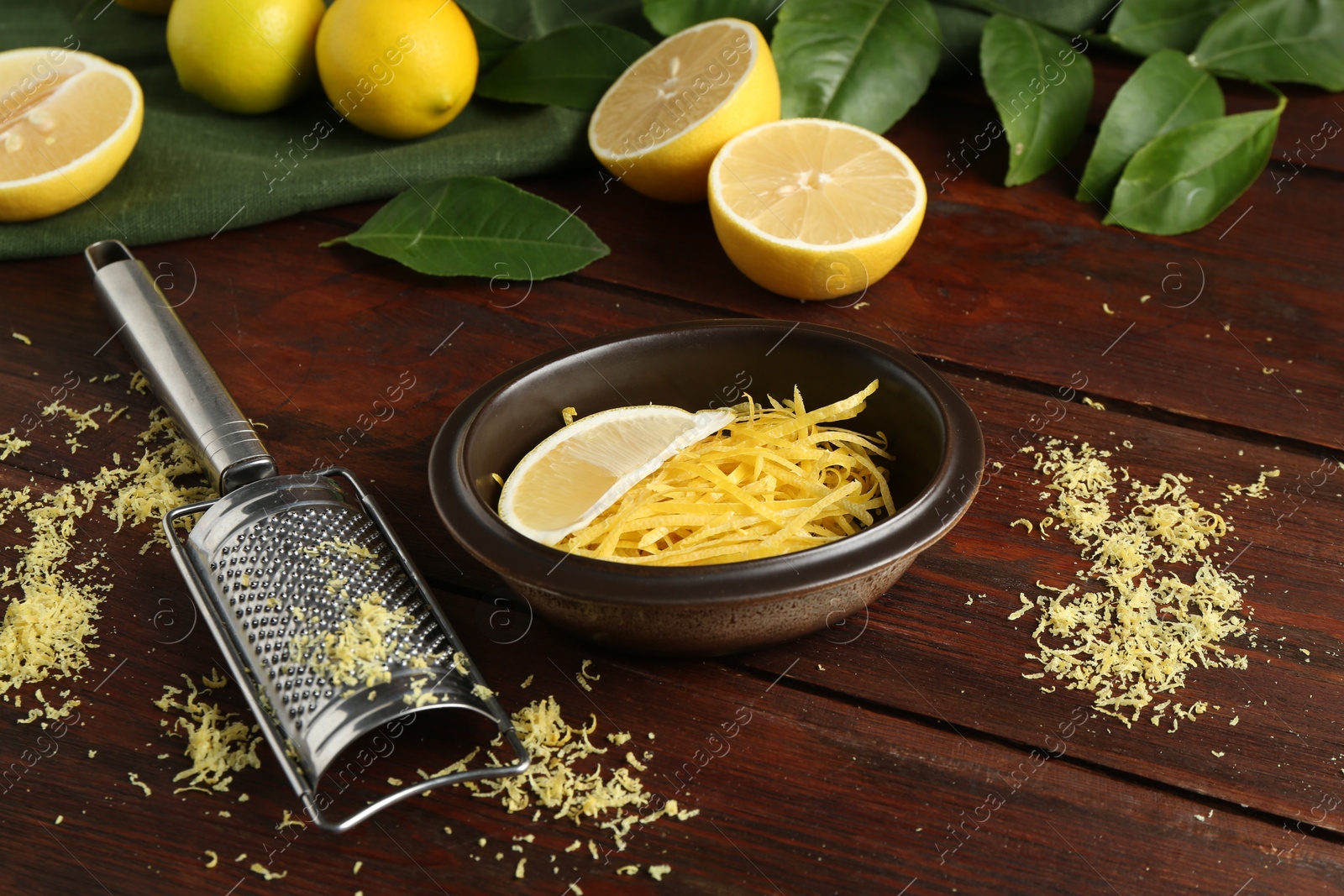 Photo of Lemon zest, grater and fresh fruits on wooden table