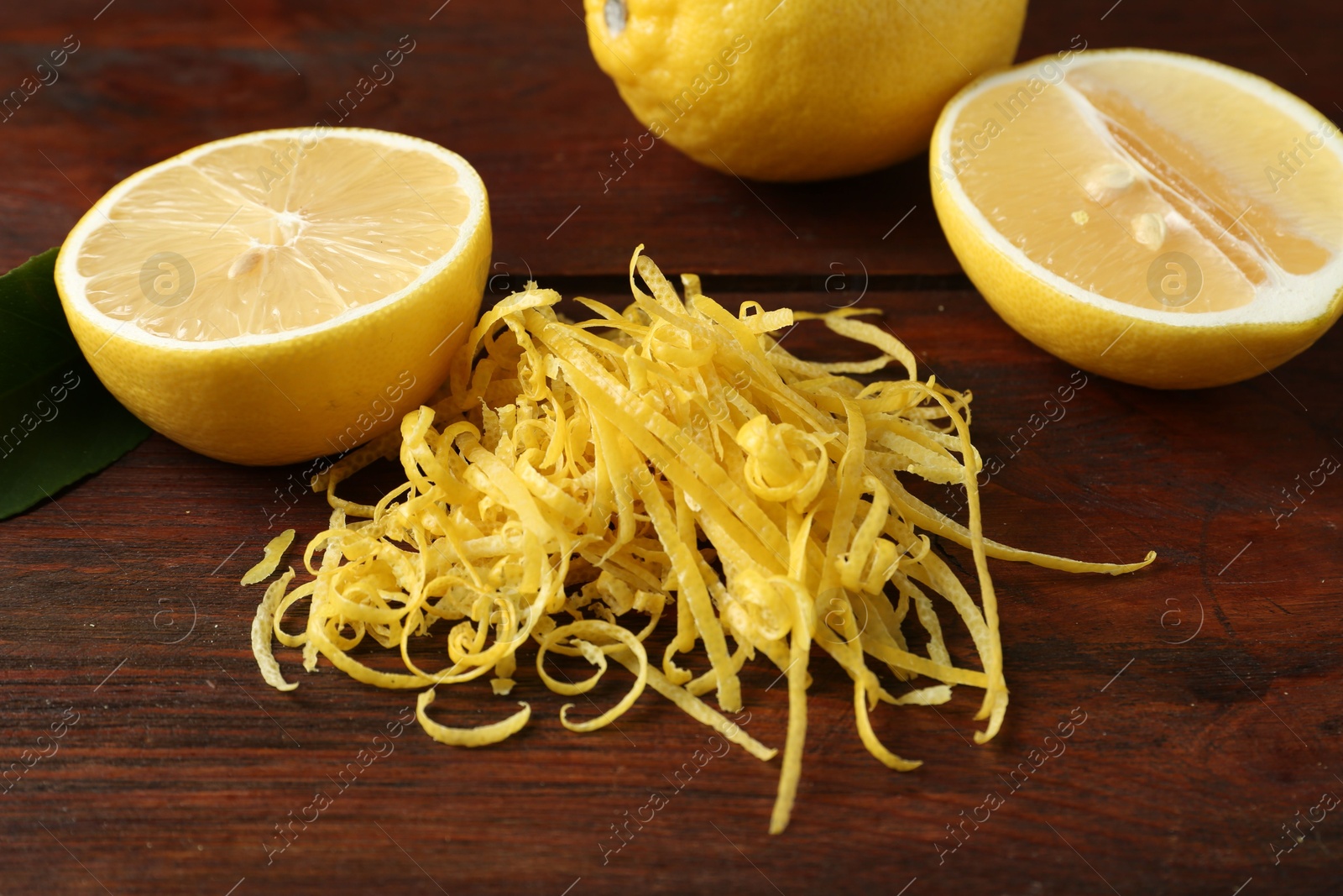 Photo of Lemon zest and fresh fruits on wooden table, closeup