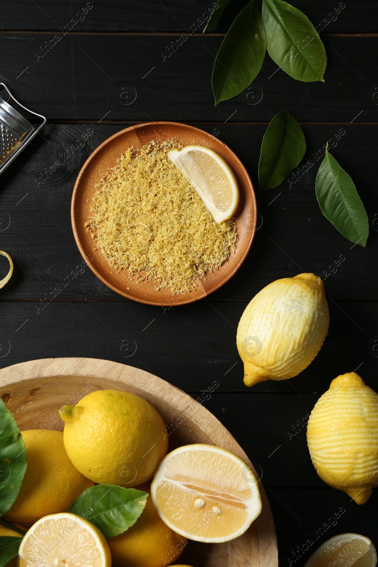 Photo of Lemon zest and fresh fruits on black wooden table, flat lay