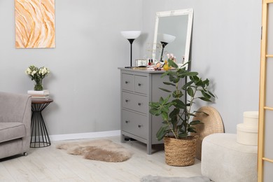 Photo of Makeup room. Mirror, dresser, different beauty products and houseplant indoors