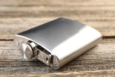 Photo of One hip flask on wooden table, closeup