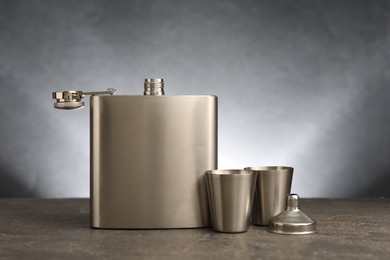 Photo of Hip flask, cups and funnel on grey table