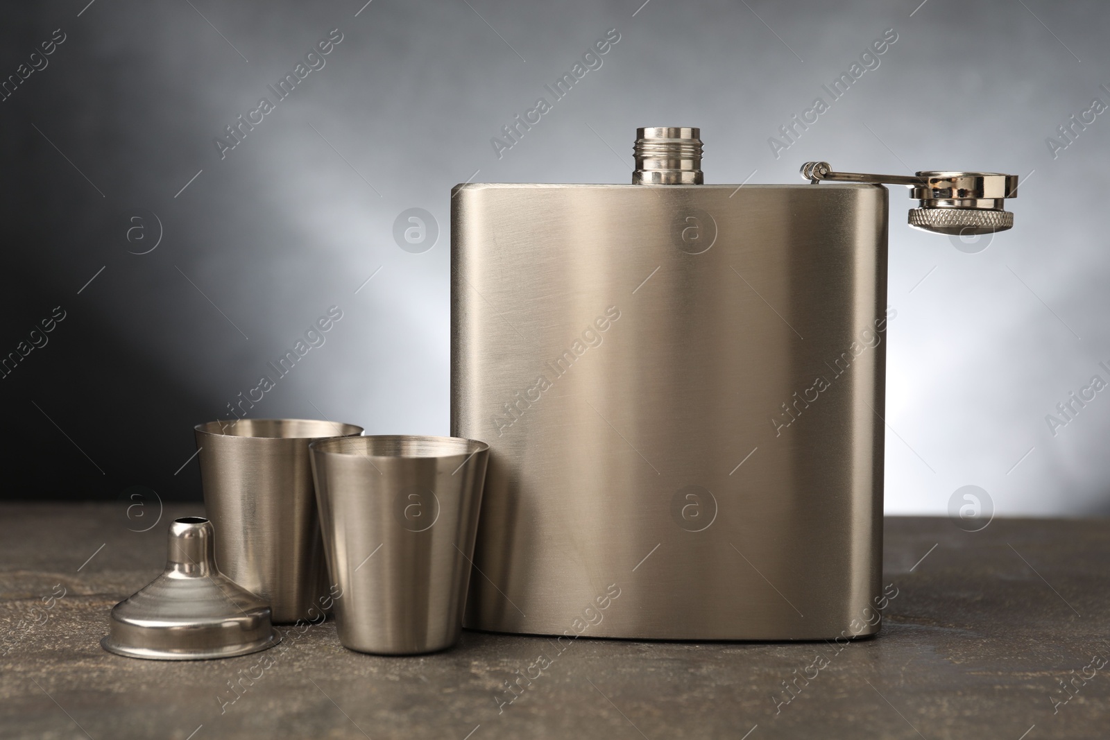 Photo of Hip flask, cups and funnel on grey table